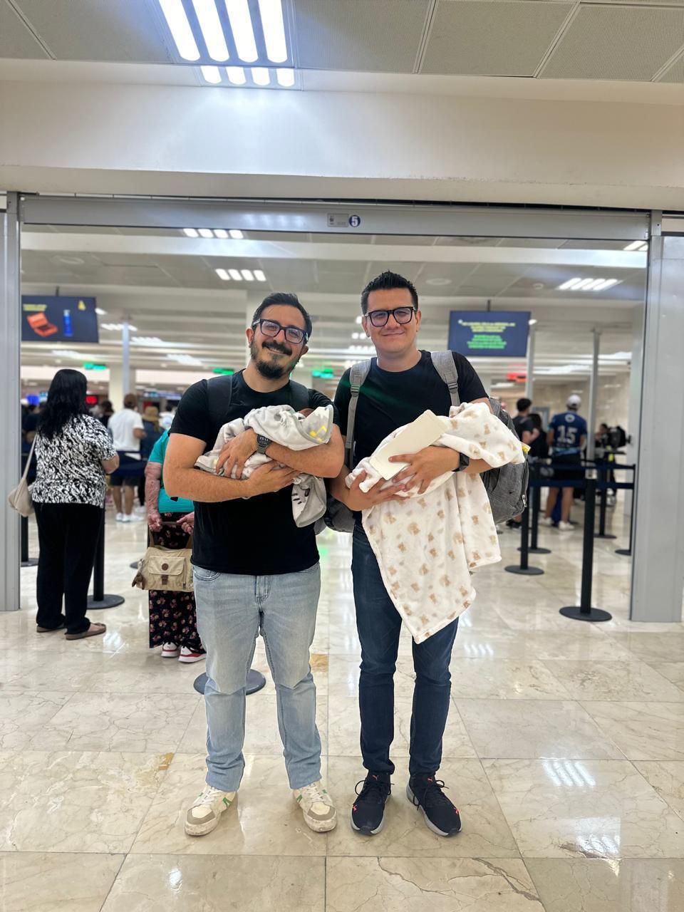 Parents at the airport flying home with their newborn twins after surrogacy in Mexico