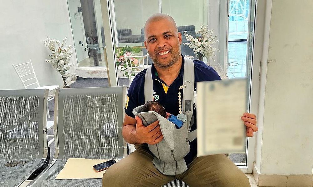 Will S., single father, holding his newborn and the Amparo birth certificate — Fertility Solutions Center